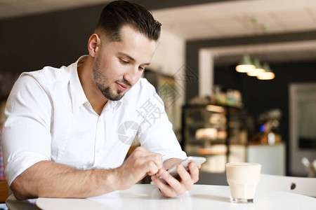 年轻商人在咖啡馆用智能手机聊天图片