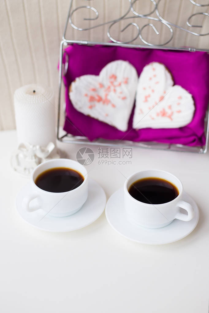 两杯咖啡饼干和蜡烛以粉红餐巾上的图片