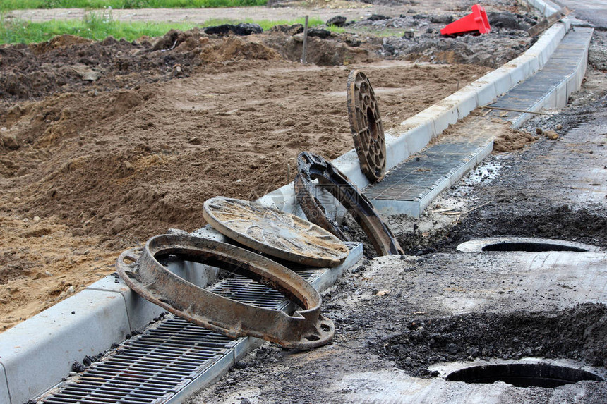 许多生锈的圆形舱口和城市道路一侧的雨水网城市出口道路的修缮和扩建Gatchina图片