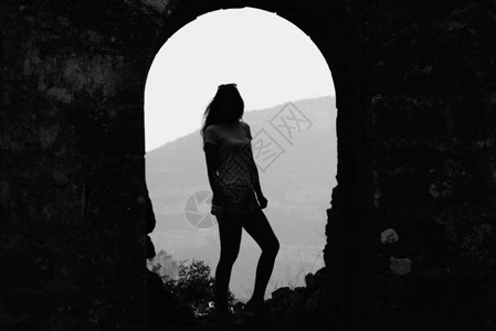 可爱的年轻女孩在t恤和短裤留在西班牙山区的石拱门山中的旅行图片