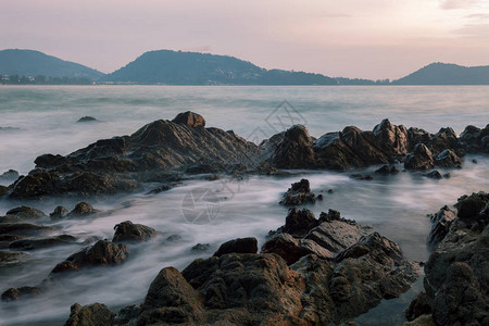 在日落风景背下以岩石绘制的戏剧天空和波浪海景图片