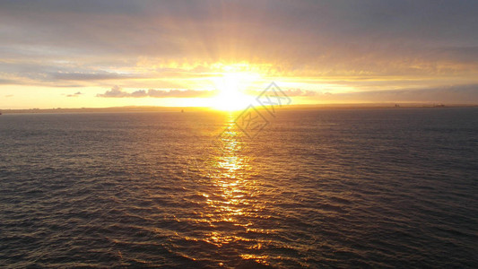 太阳升起的光束笼罩在海面和云彩中图片