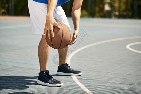 年青的男篮球运动员在法庭上打滚和练图片