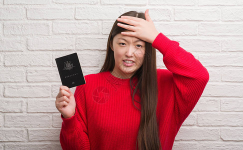 砖墙上拿着澳大利亚护照的年轻女子双手捂着头压力大图片