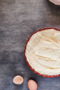 在红色圆形陶瓷馅饼烤盘中涂上黄油制作馅饼的概念最小的深色食物摄影造型垂直图片