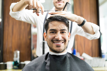 年轻男客户在接受美发店理发师服图片