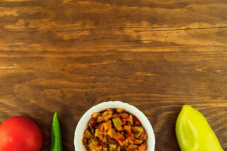 用西葫芦西红柿辣椒洋葱和胡萝卜在木制背景上的白盘中炖蔬菜鱼子酱图片