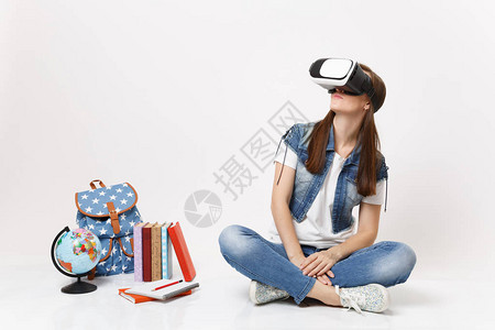 戴着虚拟现实眼镜的年轻黑发女学生一边看一边享受坐在地球附近背包孤立在白色背景上的课本学校大学院背景图片