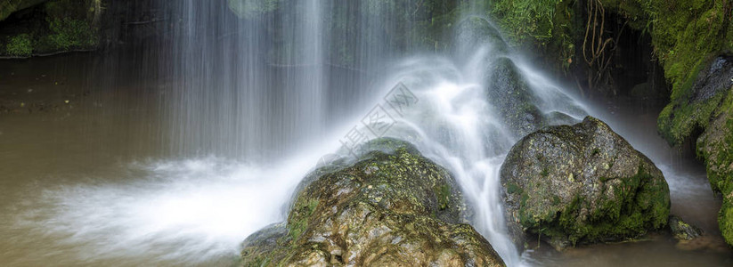 长时间曝光在绿色岩石上的瀑布流全景拍摄图片