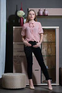 穿着粉色衬衫和黑色裤子的女孩站着摆姿势图片