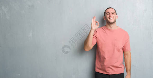 青caucasian男子在灰色的墙壁上微笑着正面图片