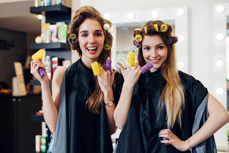 两个女孩卷发和卷毛穿斗篷的卷发笑得很开心在美发店把滚图片