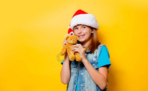 年轻少女戴圣诞帽子的肖像画和黄色的泰迪熊Teddy图片