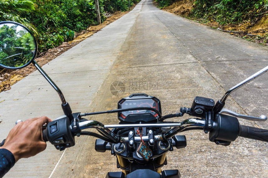 在农村乡公路深森林地带驾驶摩托车的