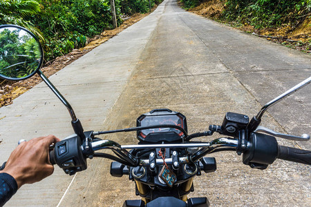 在农村乡公路深森林地带驾驶摩托车的图片