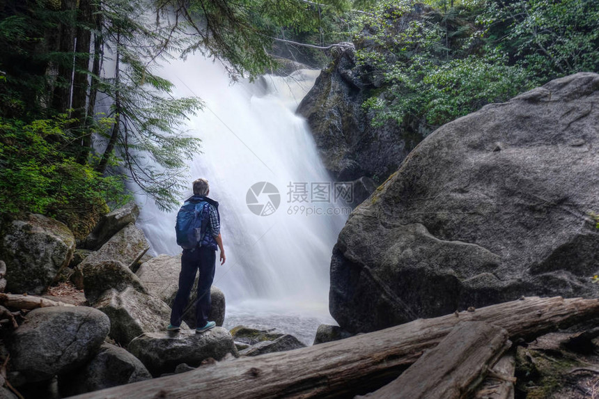 站在岩石上的瀑布附近的女人惠斯特的春假彩虹瀑布在彩虹河上加里波第省立公园惠斯勒不列颠哥伦比图片