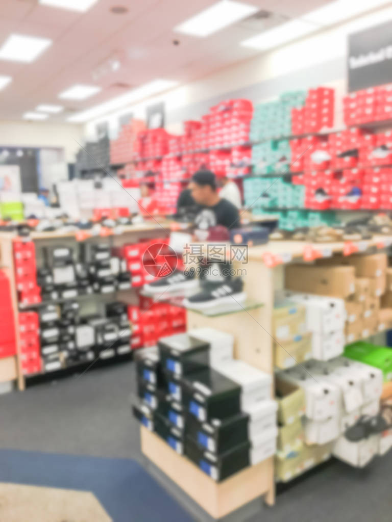 美国的模糊图像鞋类零售店在木架子或全新的盒子排上展示的大量不同鞋子的散焦顾客购买休闲鞋运图片