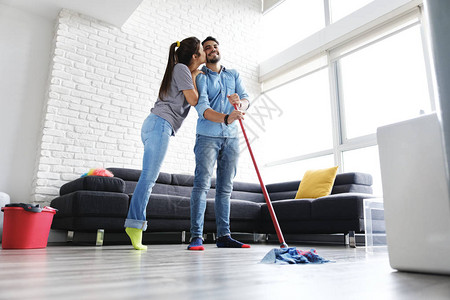年轻夫妇做家务和家务男人和女朋友用拖把擦地板女人为她的丈夫感到图片