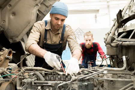 年轻集中的高加索男技师在服务车库修车图片