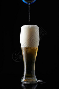 在高玻璃杯中倒啤酒孤立图片
