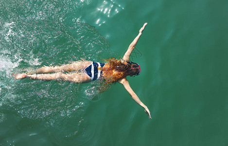 空中自上而下看到一个穿白蓝泳衣的女孩在海中背景图片