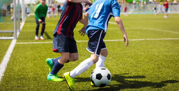 青少年足球比赛两名年轻的足球运动员奔跑和争夺球青图片