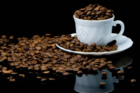 黑色背景中带豆子的白咖啡杯背景图片
