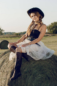一名身着女牛仔服装的年轻女子在日落时站在农民田玉米田里图片
