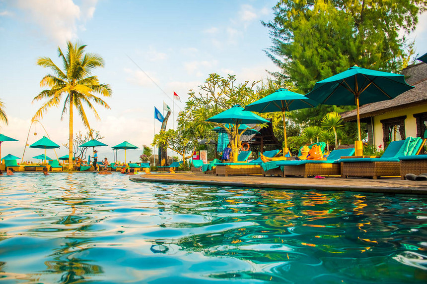 热带度假村游泳池附近的沙滩椅或日光浴床图片