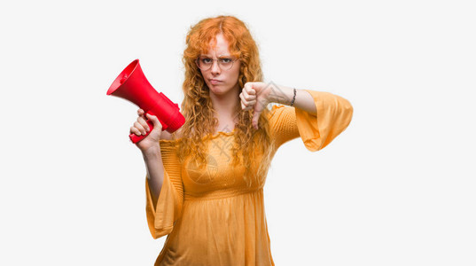 年轻红发妇女带着愤怒的脸的扩音器反表情示不喜欢低拇指的负面迹图片