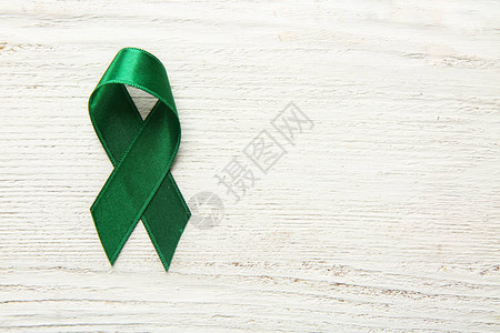 木制背景上的绿丝带癌症概念图片