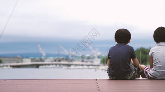 坐在日本小樽北海道港口或海上码头前的家人的照片背后图片