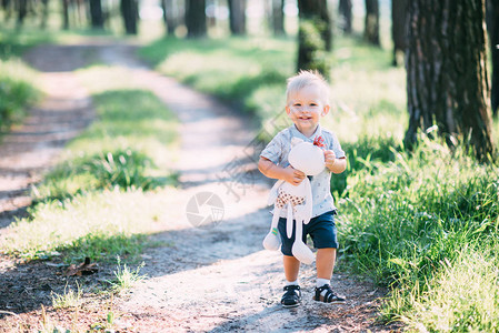 这小男孩站在森林的路上手里拿着一个图片