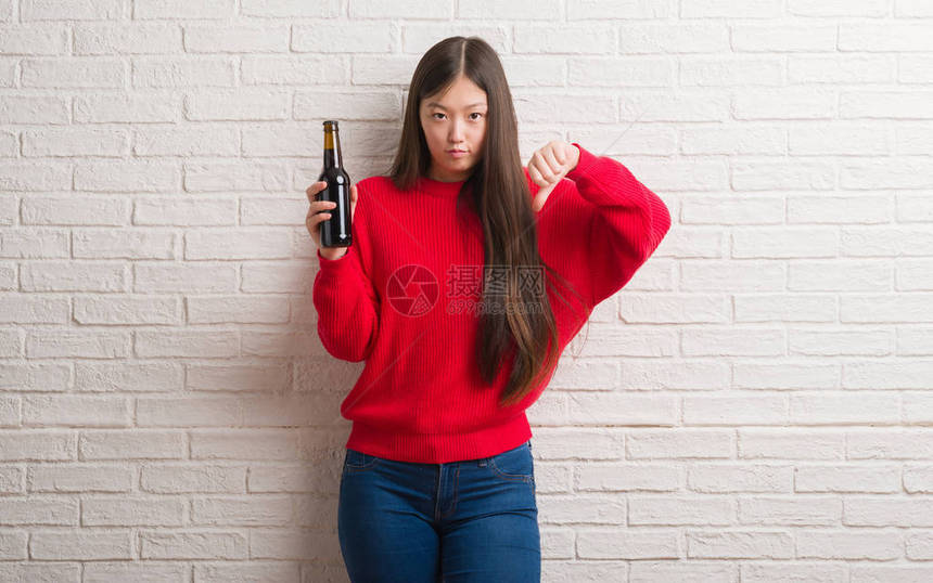 青华女子在砖墙上喝着啤酒图片
