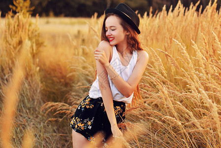 漂亮的少女模特戴着帽子在春天的田野上奔跑图片