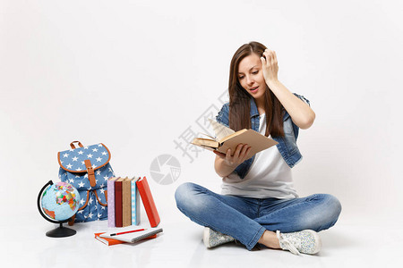 穿着牛仔服的年轻兴奋的女学生拿着书读着图片