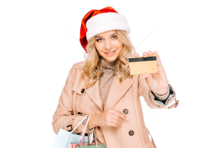 戴着圣塔帽拿着购物袋和信用卡的美丽笑着微图片