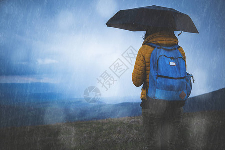 一个女孩在雨中撑伞的剪影图片