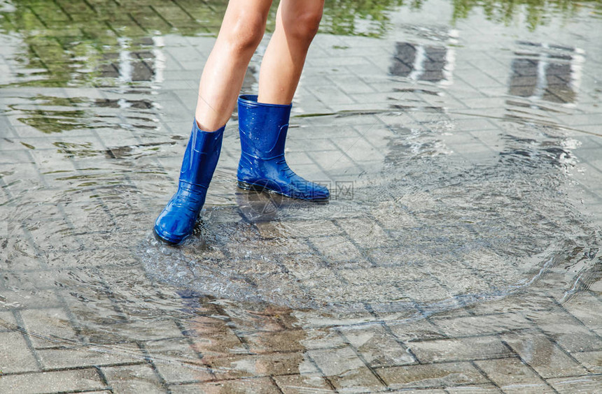 穿着橡皮靴的女孩在夏日户外下雨后图片