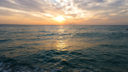 海面日落时太阳在云中图片