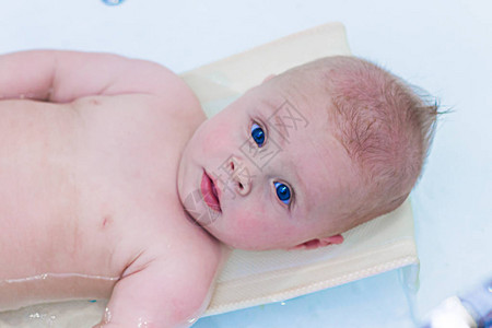 个月的男婴洗澡浴缸里的小孩婴儿洗涤和沐浴无法辨认的母亲给图片