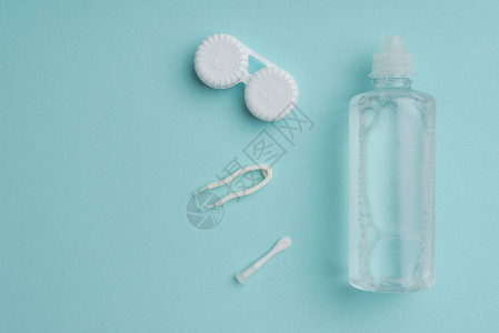 瓶tweezers和蓝色桌面隐形眼镜容器中的无菌液背景图片
