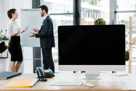 业务同事在办公室桌面上讨论白板工作和空白电脑屏幕图片
