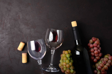 红酒瓶子葡萄和软木塞躺在深色木制背景上的酒杯顶视图平图片