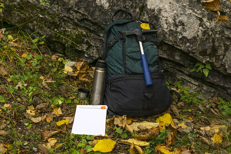 野外地质学家的装备背包地质锤热水瓶和野外记事本位于岩背景图片