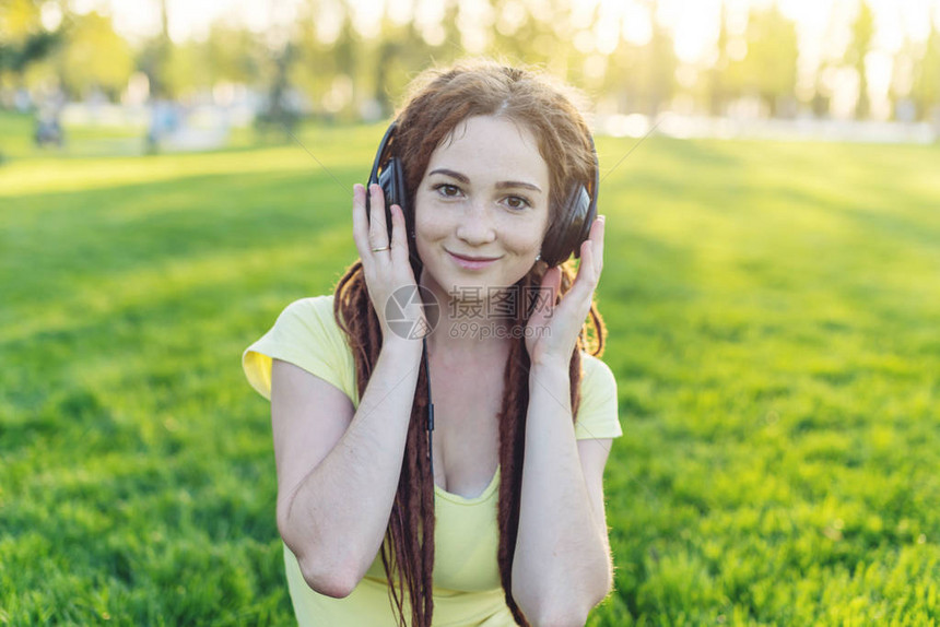 美丽的现代女在秋天阳光公园的自然背景下用耳机听音乐好心情最喜欢的音乐快图片