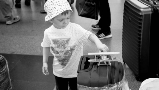 小蹒跚学步的男孩在机场航站楼玩具飞机的黑白照片孩子旅行图片