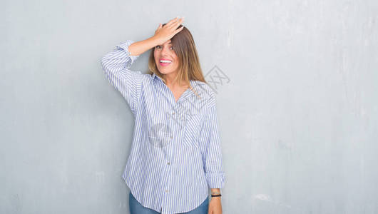 年轻的成年女在灰色的垃圾墙上穿着时尚的商务装图片