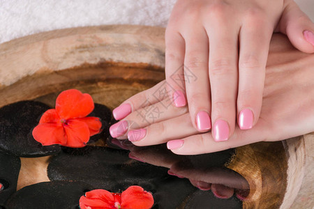 女孩手在水上指甲上指甲上钉着粉红色凝胶油美工图片