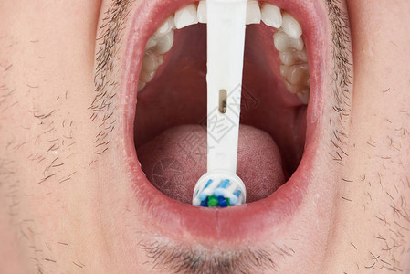 用电动牙刷清洁牙齿的张开嘴图片